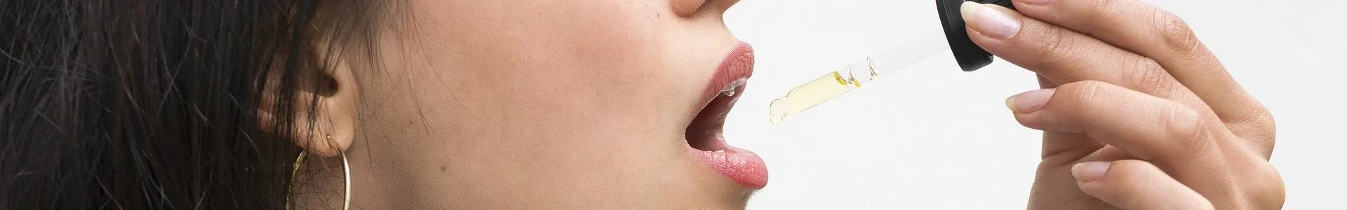 Een vrouw druppelt biologische CBD olie in haar mond