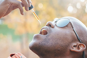 Een man druppelt biologische CBD olie in zijn mond