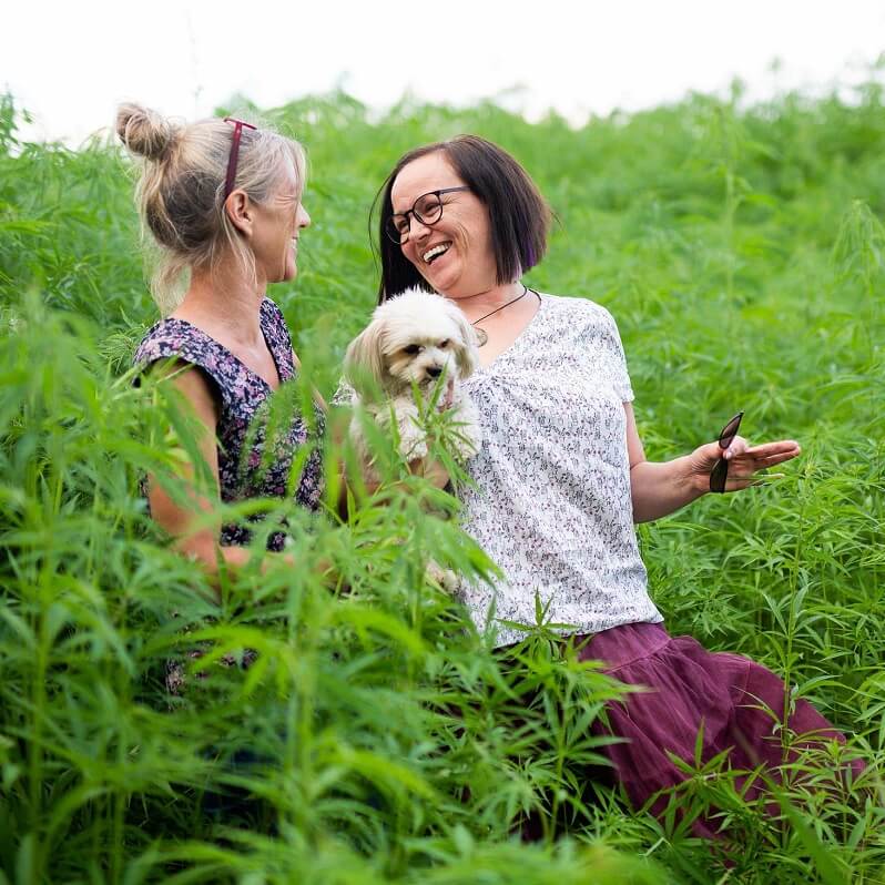 Andrea Bamacher en Elke Moritz met hond in een veld met hennep