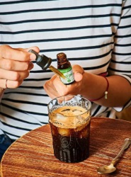 Iemand druppelt CBD olie in de koffie